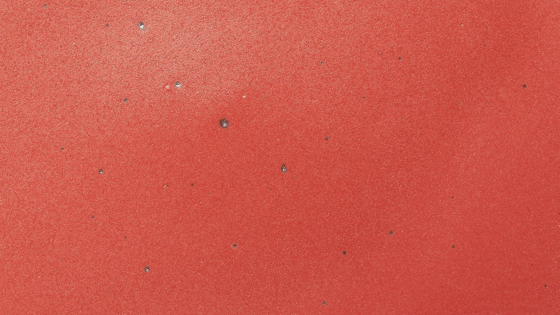 A closeup of a ceramic plate in a bold red color featuring iron speckles