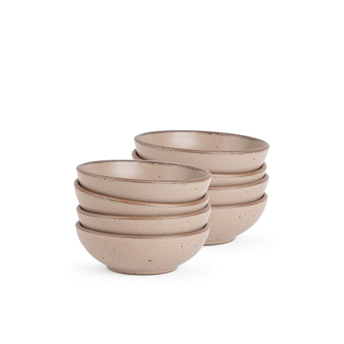 A stack of 8 small shallow ceramic bowls in a warm pale brown color featuring iron speckles and an unglazed rim