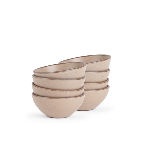 A stack of 8 small dessert sized rounded ceramic bowls in a warm pale brown color featuring iron speckles and an unglazed rim