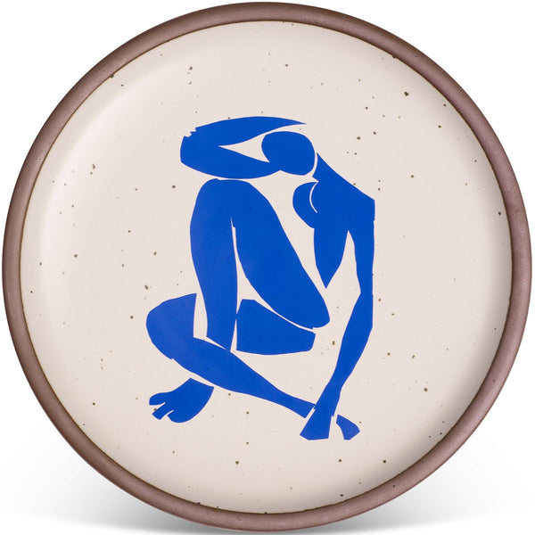 Round ceramic plate with a brown rim, featuring a bold blue abstract figure on a speckled beige background.