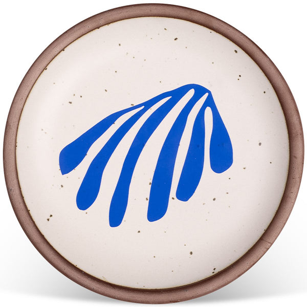 Round ceramic plate with a speckled off-white surface, featuring a bold blue abstract design and a brown rim.