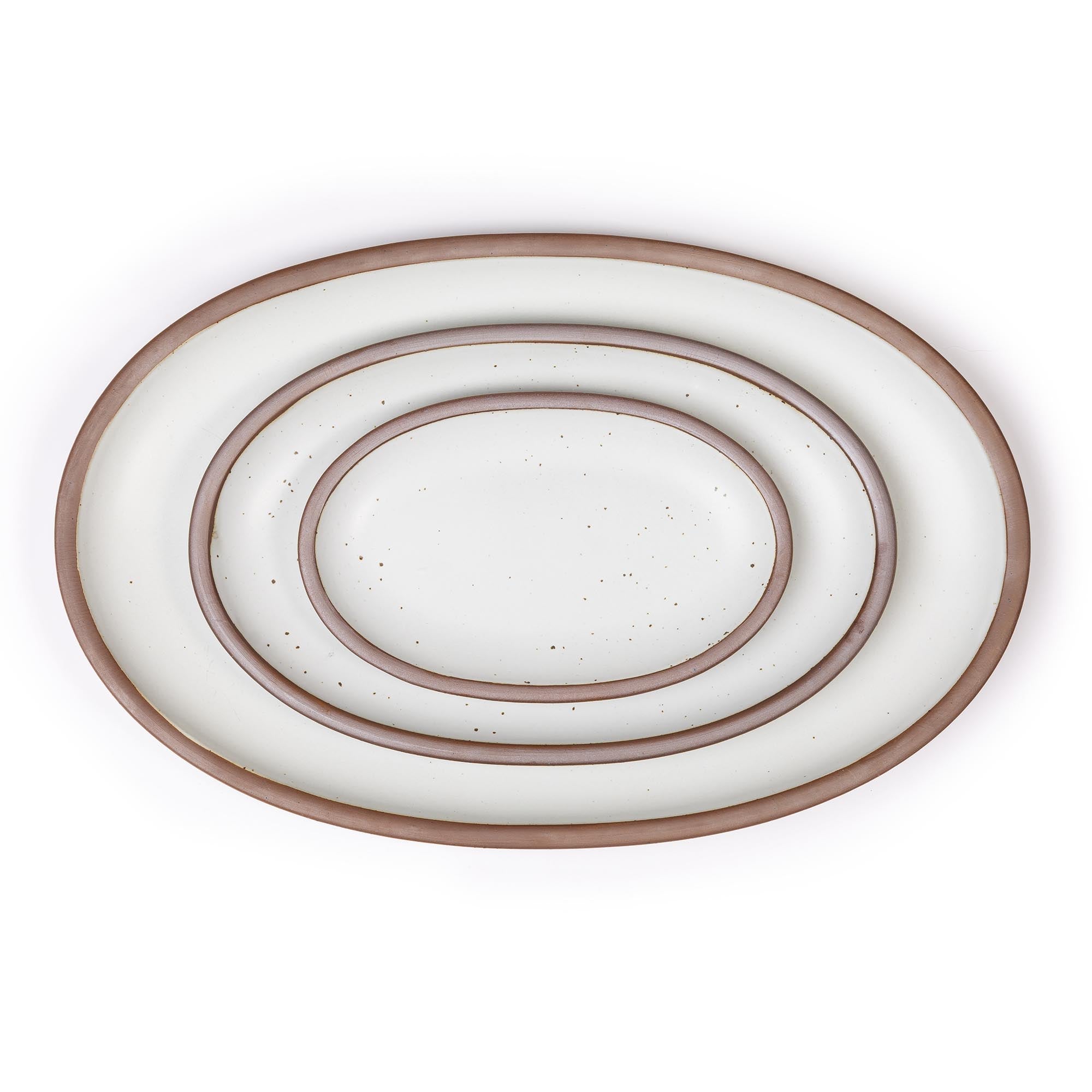 Set of three white ceramic oval platters with unglazed rim nested together on a white background