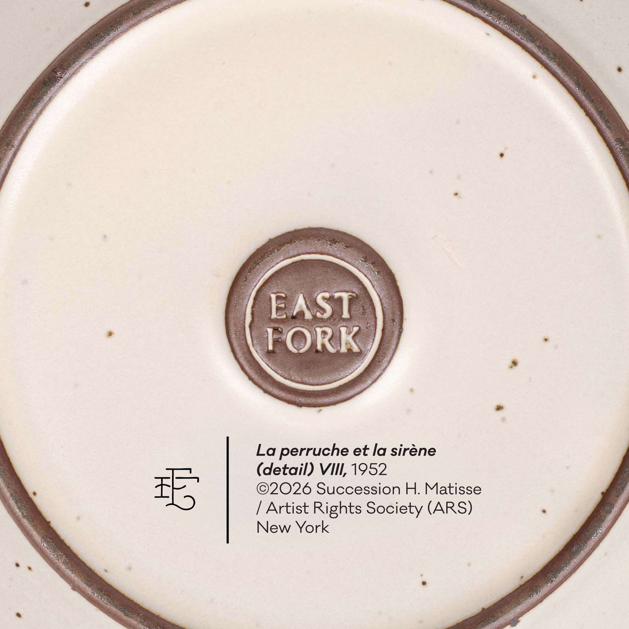 Close-up of the bottom of a ceramic plate or dish showing a circular brown brand mark reading EAST FORK in the center, with printed text below including 'La perruche et la sirène (detail) VIII, 1952' and artist/rights information.