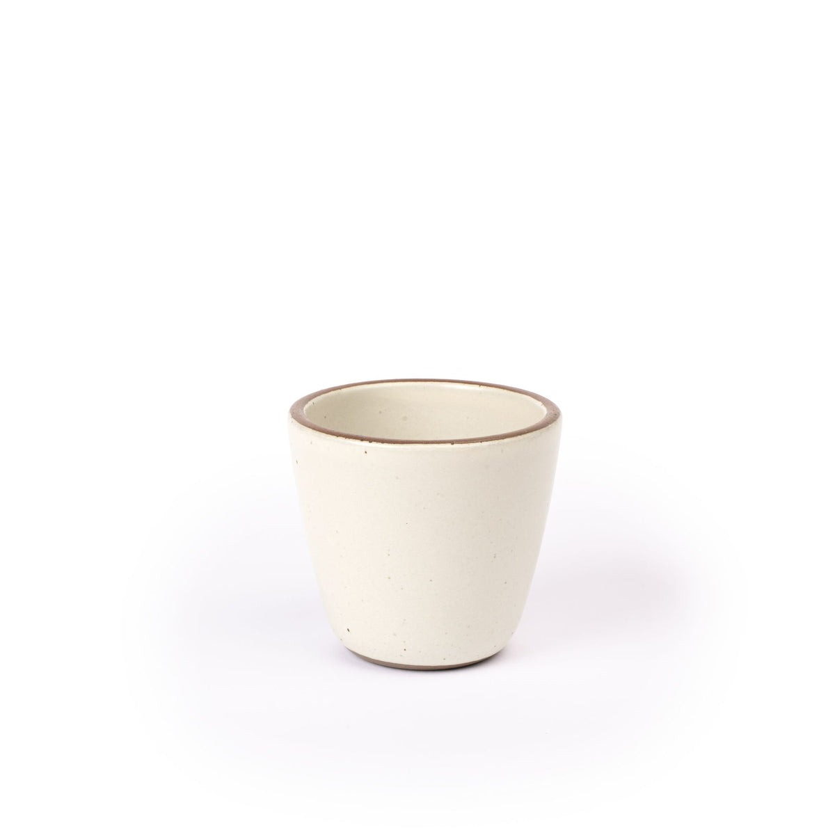A short cup that tapers out to get wider at the top in a warm off-white color featuring iron speckles