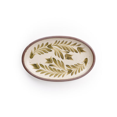 A medium oval ceramic platter in a warm, tan-toned, off-white color featuring iron speckles and an unglazed rim, with handpainted greenery in an olive green color.