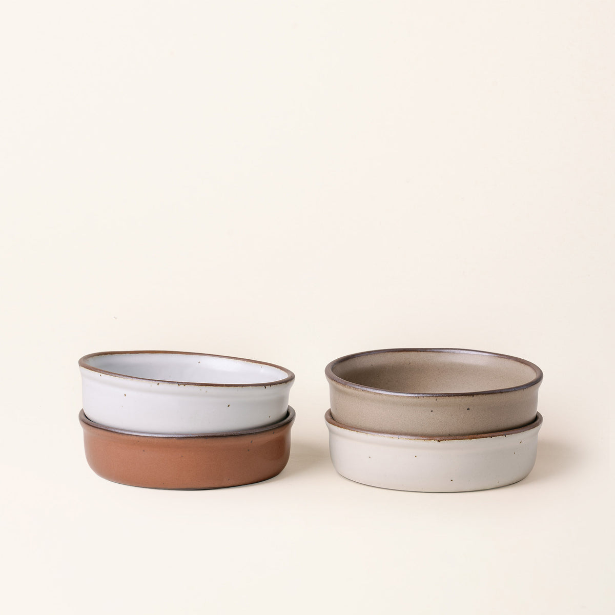 4 wide shallow ceramic ramekins in an off-white, cool terracotta, cool white, and warm pale brown color with an unglazed rim.