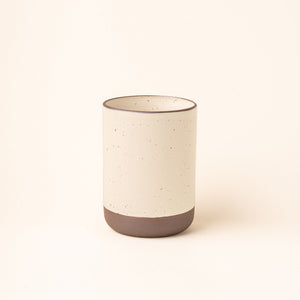 A cylindrical ceramic utensil crock and an unglazed base, in a warm off-white color.