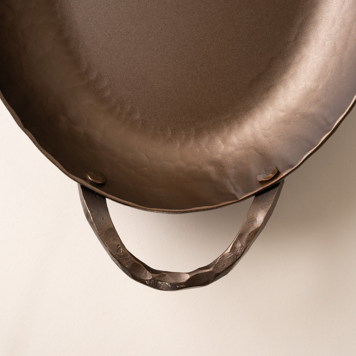 A closeup of the handle of a hammered metal oval roasting pan