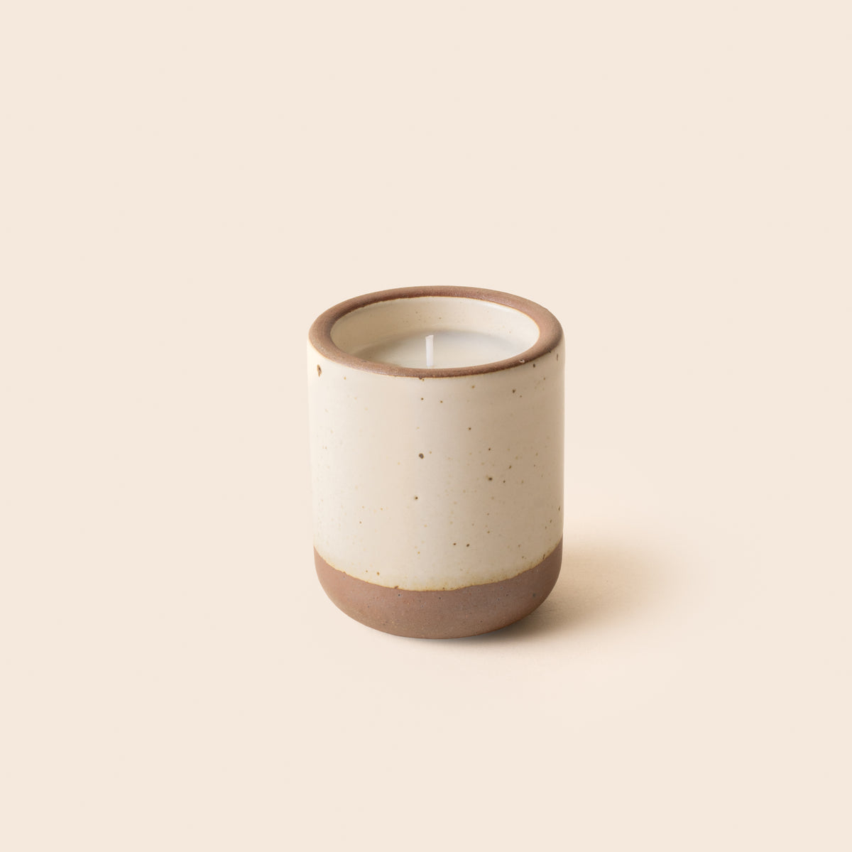 Small ceramic vessel in a warm off-white color with candle inside.