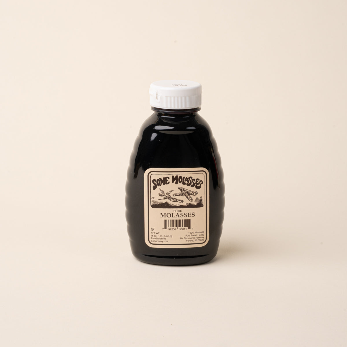 Bottle of pure molasses with a white cap on a plain white background.