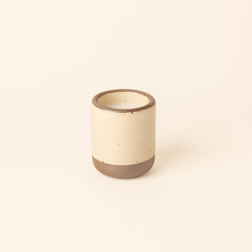 Small ceramic vessel in a cream color with candle inside.