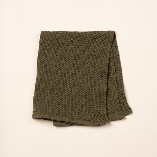 A folded olive green waffle weave kitchen towel