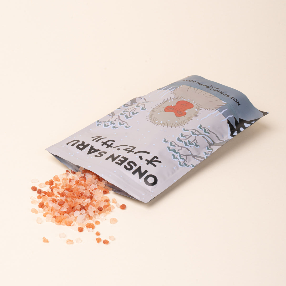 Onsen Saru Hot Spring Bath Soak with pink mineral salts spilling from its illustrated pouch.