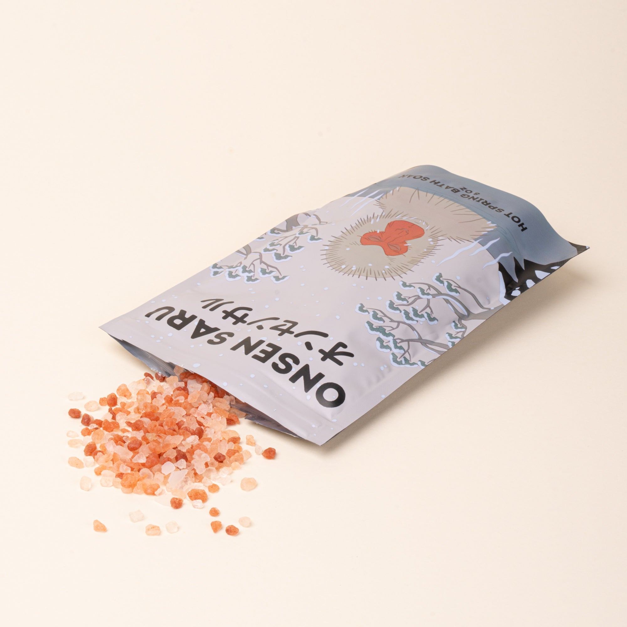 Onsen Saru Hot Spring Bath Soak with pink mineral salts spilling from its illustrated pouch.