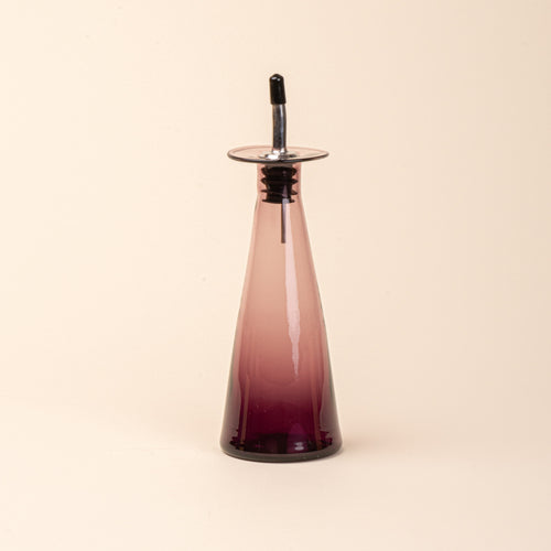 A plum glass oil or vinegar dispenser with a tapered bottle shape, wide flared collar, and metal pour spout with a black stopper.