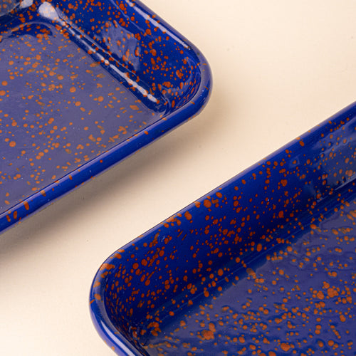 Closeup of rectangular baking dishes in a midnight blue color with red splattered pattern