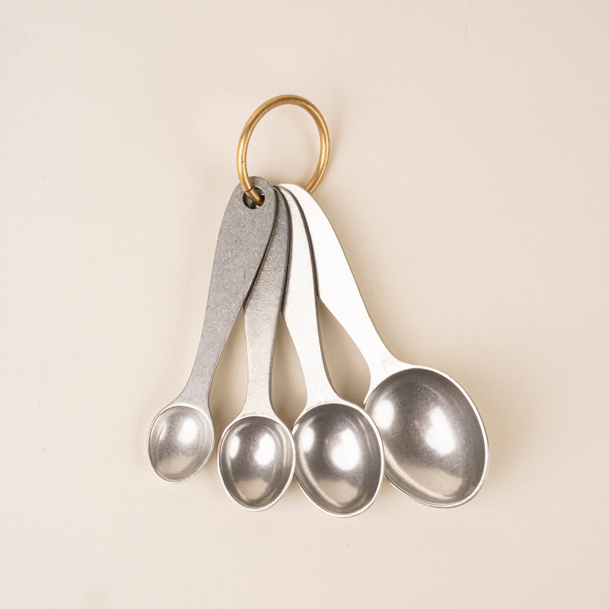 Four pewter measuring spoons on a brass ring.