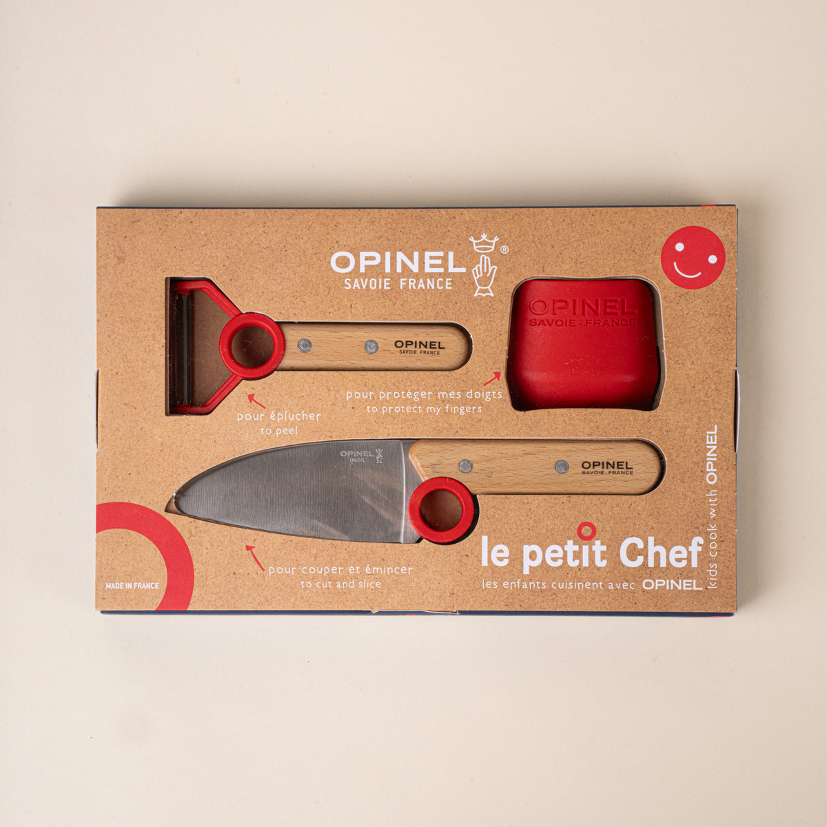 Opinel packaging box of Kitchen tool set for children with a peeler, chef’s knife, and red scraper, each with red accents.