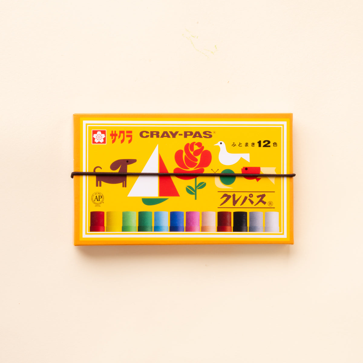 Yellow and orange Sakura Cray-Pas box of 12 oil pastels with colorful illustrations and a black elastic band across the front.