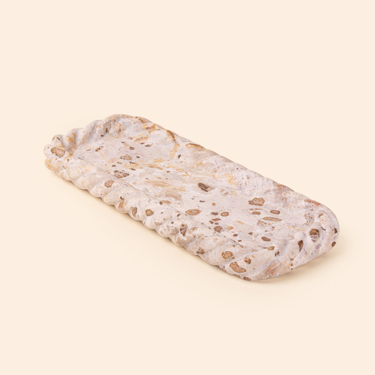 Rectangular cream and brown speckled stone tray with a shallow recessed center and irregular scalloped edges.