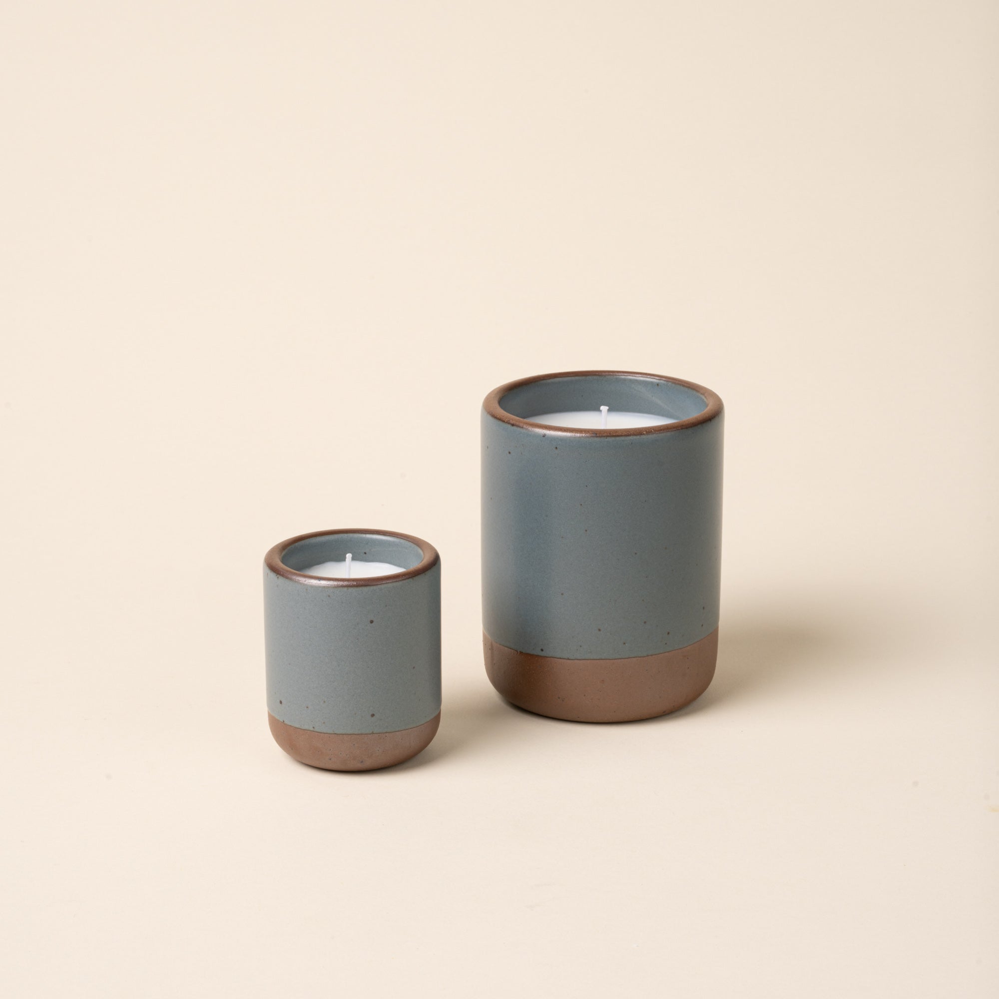 Small and large ceramic vessels in a blue-grey color with candle inside.