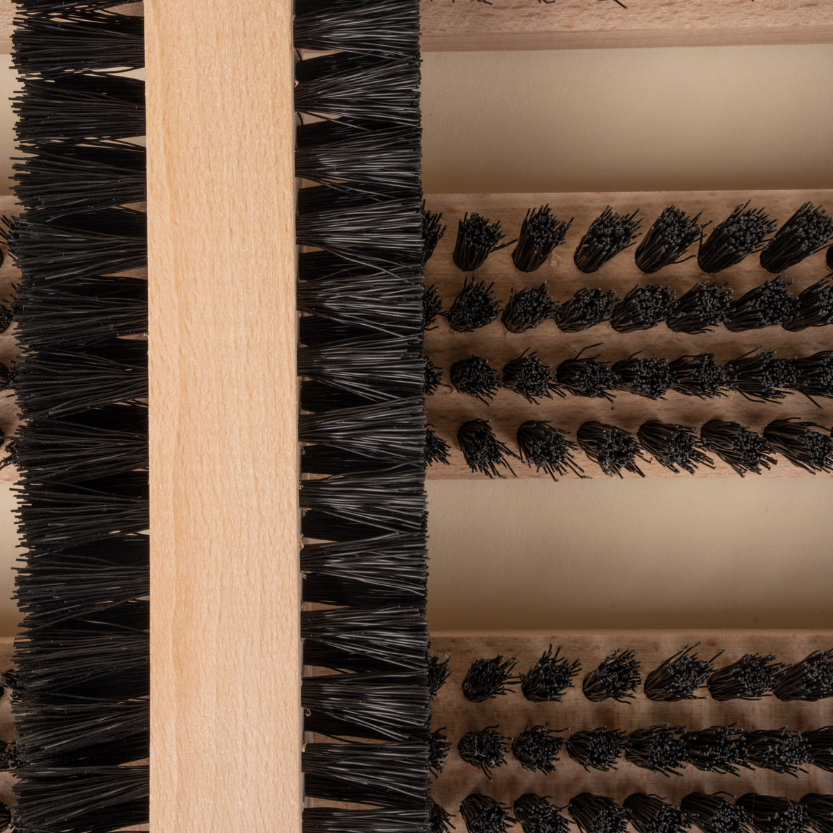 Closeup of a wooden boot and shoe cleaning brush with multiple bristle sections.