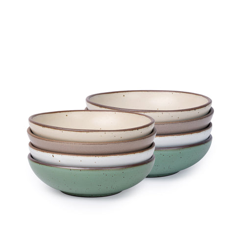 Two stacks of shallow ceramic bowls in mixed earth tones, including sage green, beige, and white, displayed against a white background.