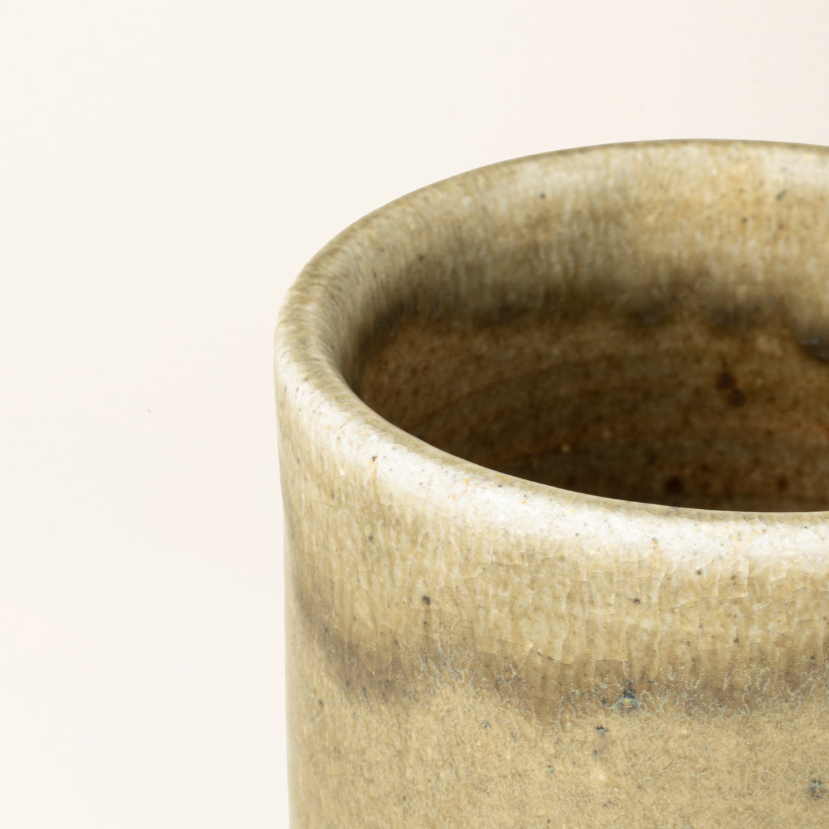 Closeup of the rim of a handmade ceramic mug with a wood fired light earthy green glaze.