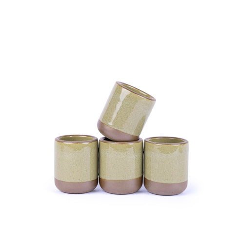 A stack of 4 tiny ceramic cups in a reflective dappled grey-green color featuring an unglazed rim and bottom base