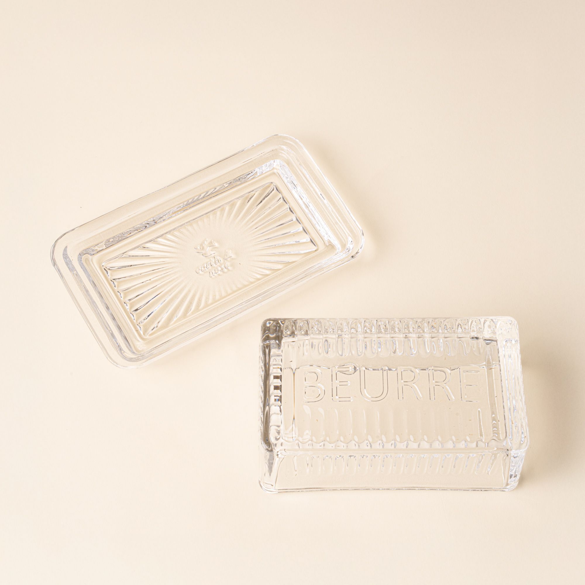 Clear glass butter dish with lid and base on a light background