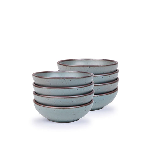 A stack of 8 small shallow ceramic bowls in a blue-grey color featuring iron speckles and an unglazed rim