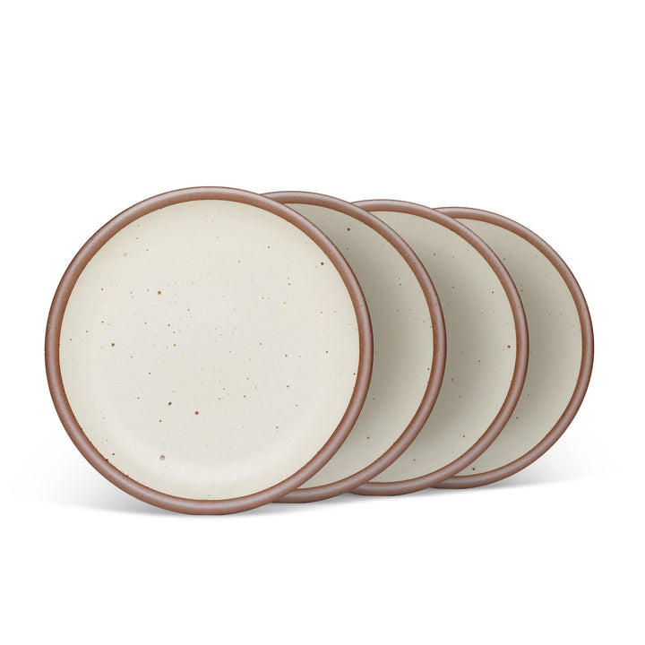 4 medium sized ceramic plates in a warm, tan-toned, off-white color featuring iron speckles and an unglazed rim.