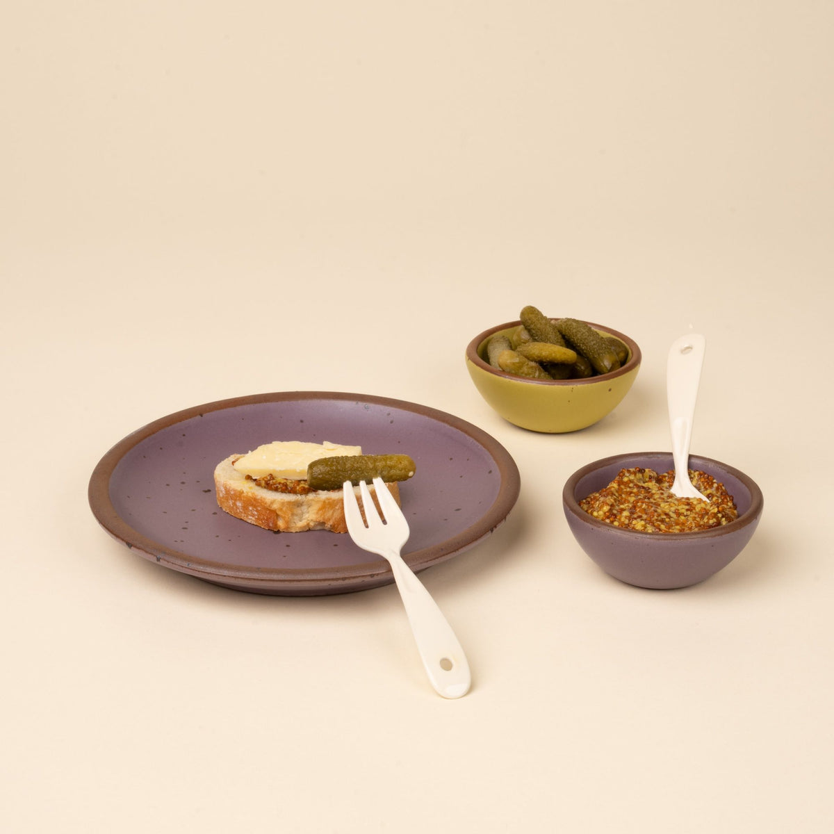 Mini fork and spoon with soft mauve purple plate and bowl with bread, dip, and mini pickles.