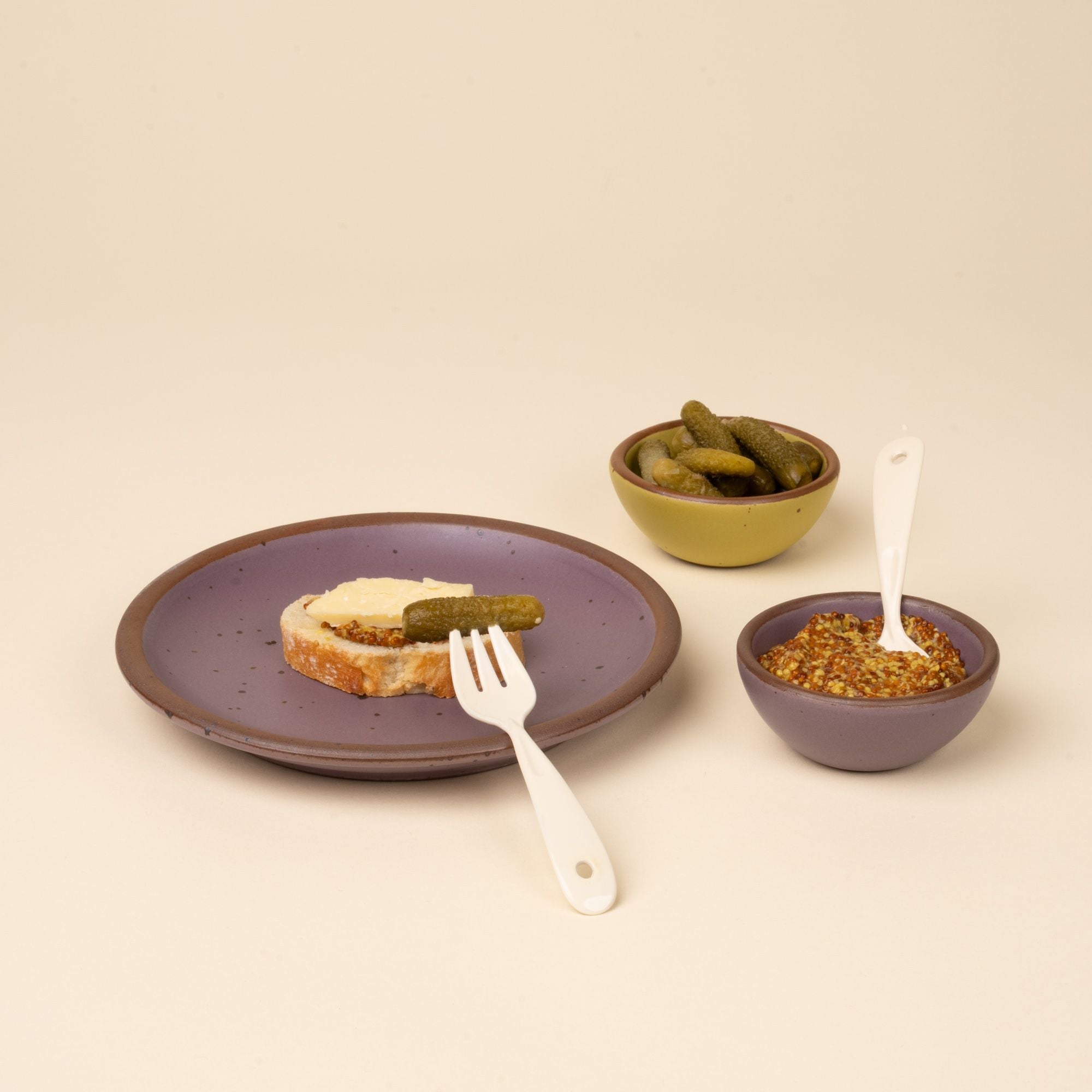 Mini fork and spoon with soft mauve purple plate and bowl with bread, dip, and mini pickles.