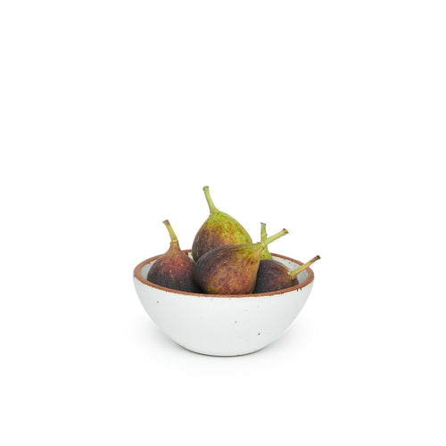 A small dessert sized rounded ceramic bowl in a cool white color featuring iron speckles and an unglazed rim, filled with figs