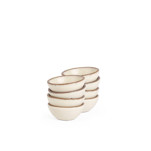 A stack of 8 tiny rounded ceramic bowls in a warm off-white color featuring iron speckles and an unglazed rim