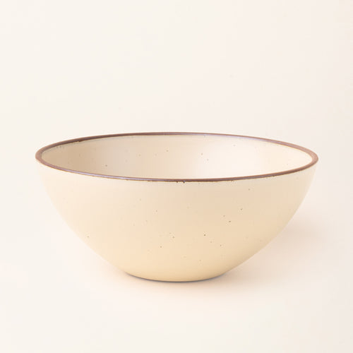 A large ceramic mixing bowl in a cream color featuring iron speckles and an unglazed rim