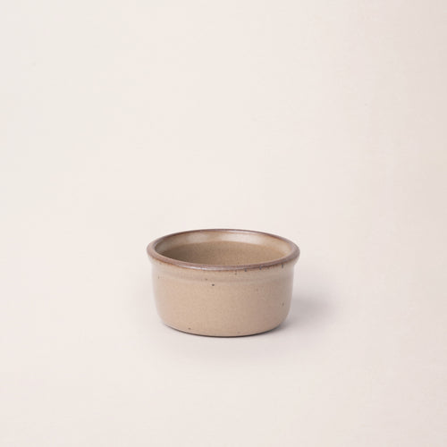 Small ceramic ramekin in a warm pale brown color with an unglazed rim