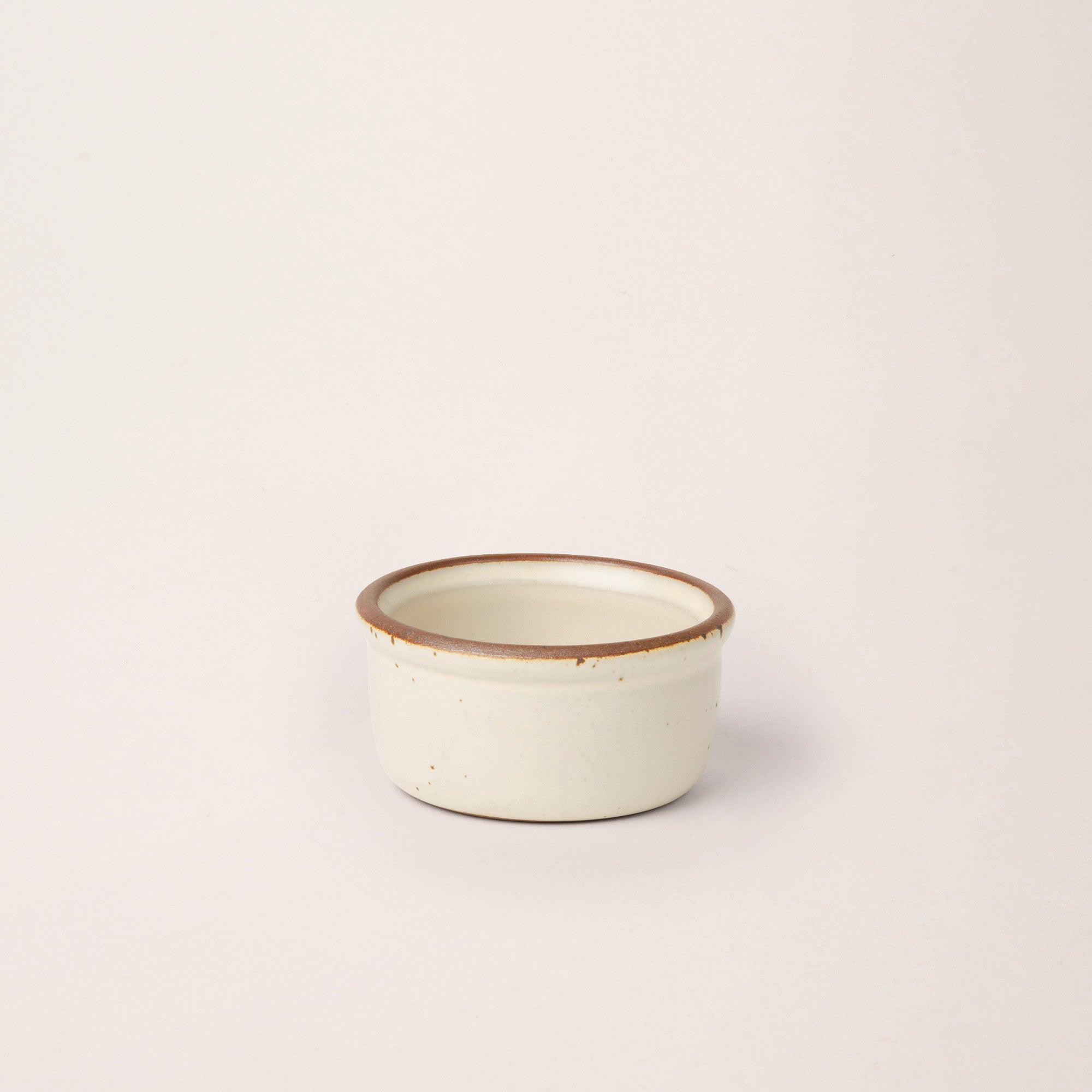Small ceramic ramekin in a warm off-white color with an unglazed rim