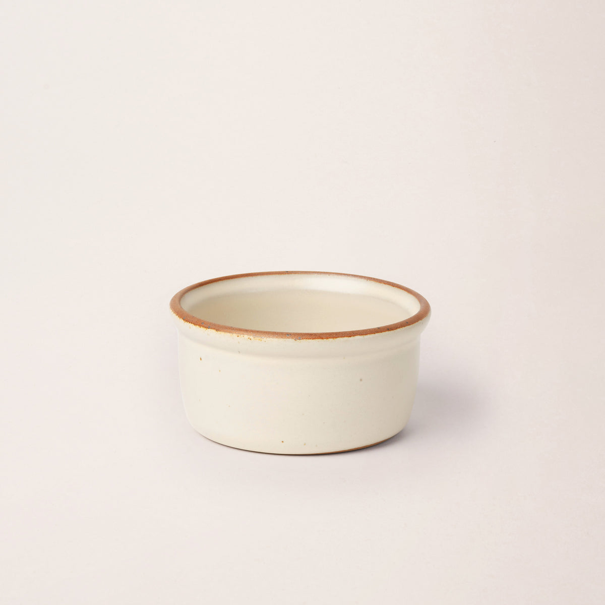 Medium ceramic ramekin in a warm off-white color with an unglazed rim