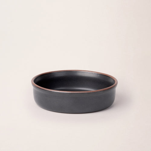 Wide shallow ceramic ramekin in a graphite black  color with an unglazed rim