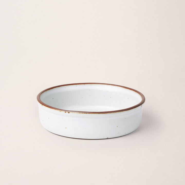 Wide shallow ceramic ramekin in a cool white color with an unglazed rim