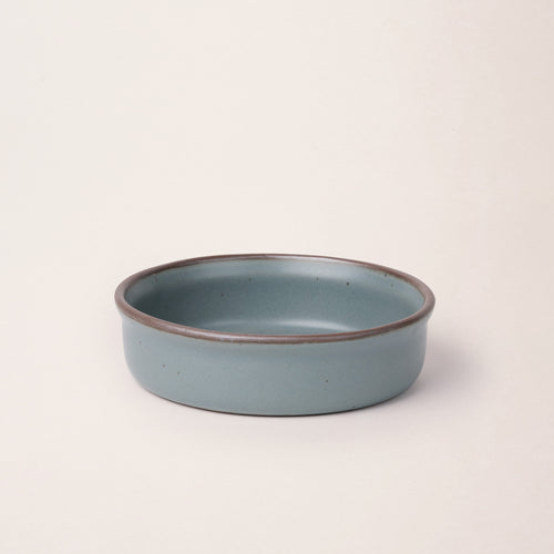 Wide shallow ceramic ramekin in a blue-grey color with an unglazed rim