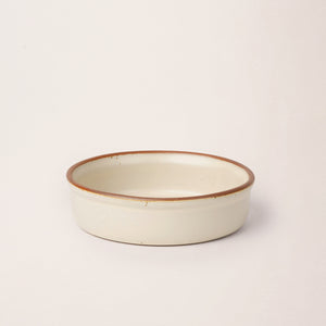 Wide shallow ceramic ramekin in a warm off-white color with an unglazed rim