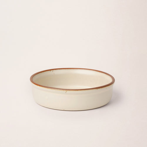 Wide shallow ceramic ramekin in a warm off-white color with an unglazed rim