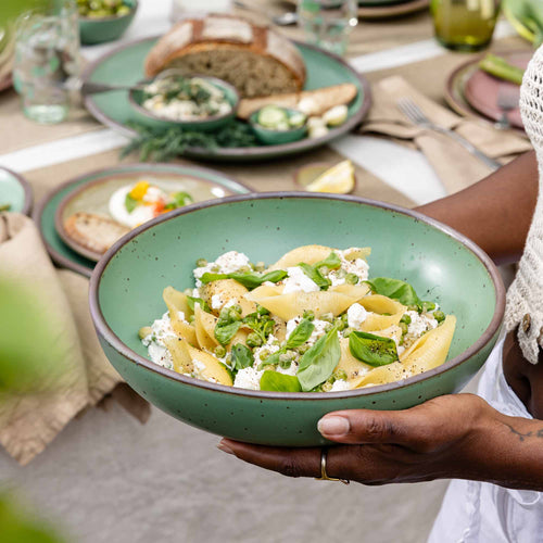 A large shallow ceramic bowl for serving at the table in a viridian green glaze with a matte finish.