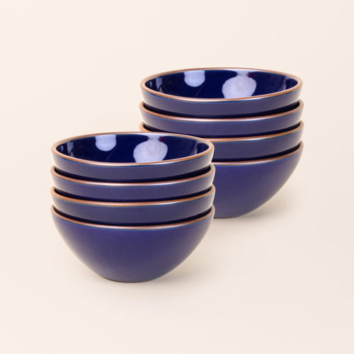 2 stacks of 4 medium rounded ceramic bowls in a glossy dark blue color featuring iron speckles and an unglazed rim