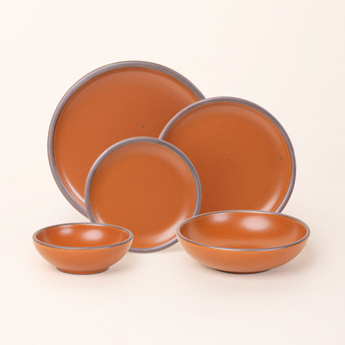 A breakfast bowl, everyday bowl, cake plate, side plate and dinner plate paired together in an earthy orange color featuring iron speckles