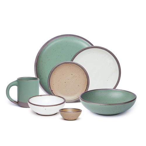 A 7-piece tablesetting set with bowls, plates and a mug in a viridian green, warm brown, warm white and cool white glazes.