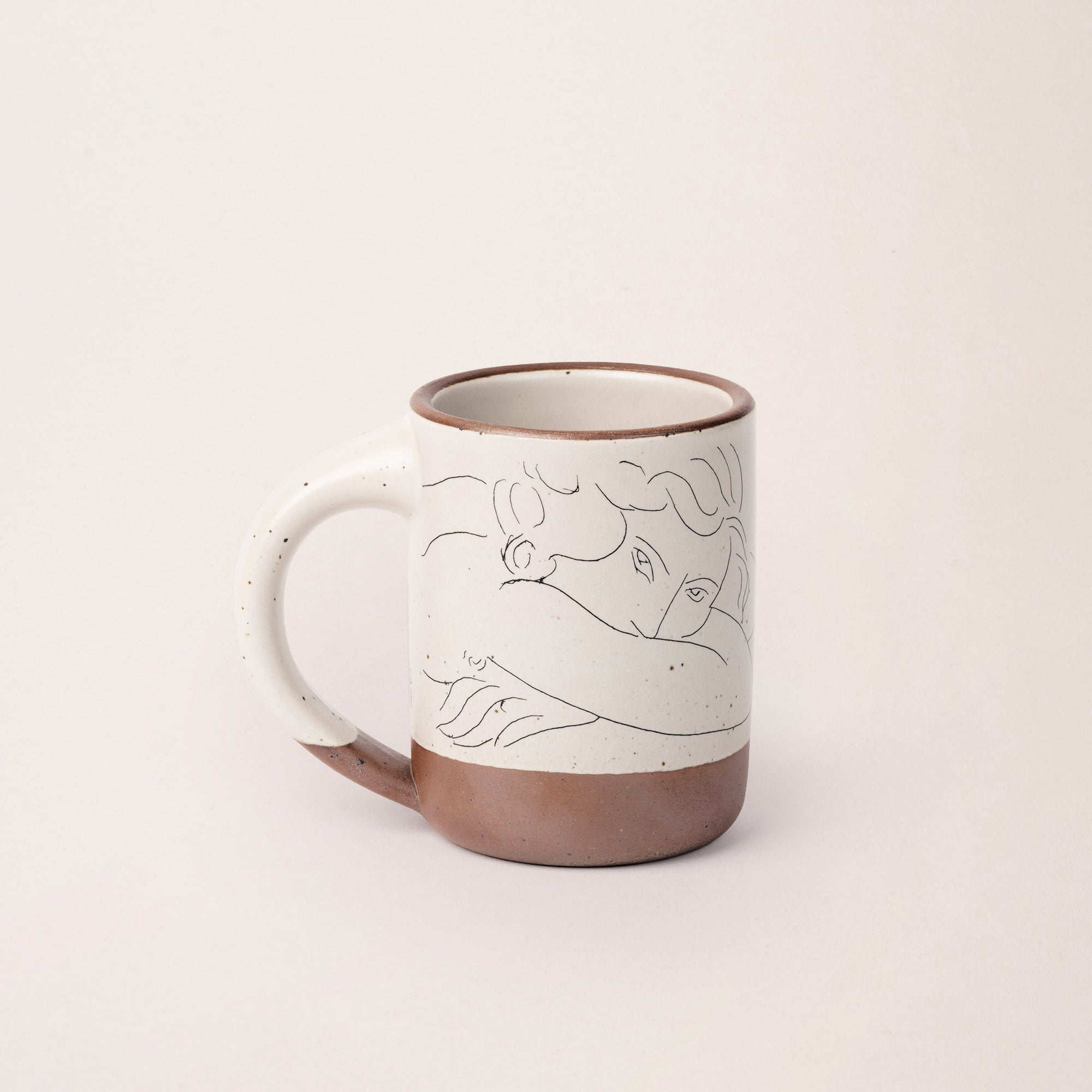 East Fork’s The Mug in a warm off white color with handle with a black decal of Henri Matisse’s Jeune femme la visage enfoui dans les bras, a bright blue, a line drawing of a young woman with face buried in her arms, on the body of the mug